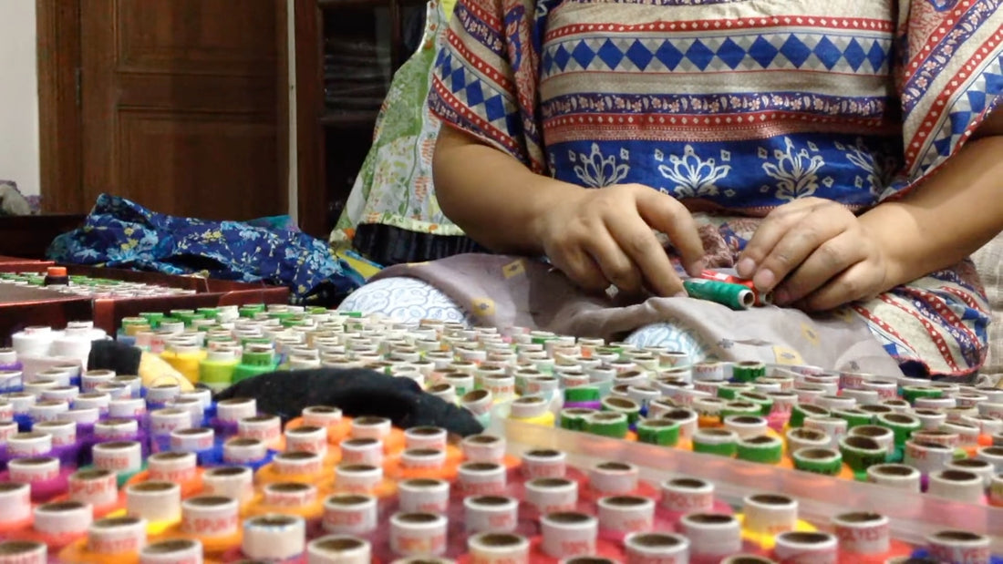 Artisan matching thread color to sari silk — step 1 of making sari silk bead necklaces