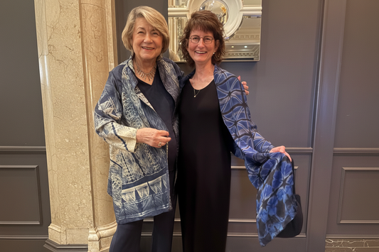 Two women at an event wearing Premaasi silk shibori pieces — a Tussar silk stitched shibori jacket and a silk shibori scarf in indigo blue